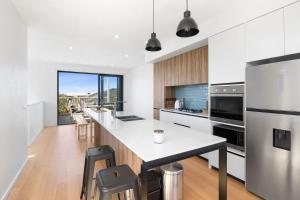 a kitchen with white counters and a large island with stools at Park View Townhouse With Rooftop Terrace in Torquay