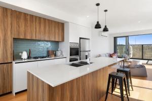 a kitchen with a white counter top and wooden cabinets at Park View Townhouse With Rooftop Terrace in Torquay