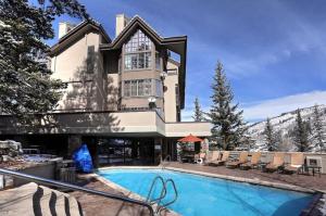 a large house with a swimming pool in front of it at Beaver Creek Pines 3 Bedroom Ski In, Ski Out Vacation Rental With Restaurant, Outdoor Pool, Jacuzzi And Fitness Center in Beaver Creek