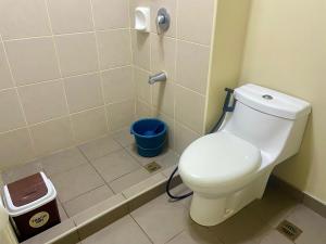 a bathroom with a toilet and a blue trash can at Avida Aspira Condotel in Cagayan de Oro