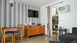 a living room with a table and a tv on a wall at Appartement Gwiggner in Niederau