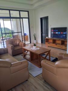 a living room with couches and a table and a television at Taylor's Country Home- The Grande by Taylor's Traveller's Inn Second Floor in Catarman