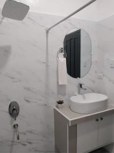 W białej łazience znajduje się umywalka i lustro. w obiekcie Taylor's Country Home- The Grande by Taylor's Traveller's Inn Second Floor w mieście Catarman