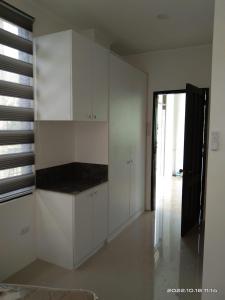 a white kitchen with white cabinets and a window at Taylors Plantacion Resort- The Grande Second Floor in Catarman