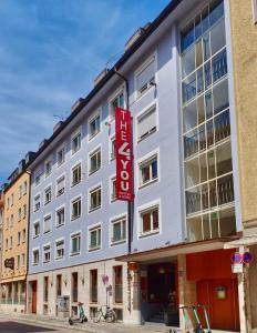a large white building with a red sign on it at THE 4YOU Hostel & Hotel Munich in Munich