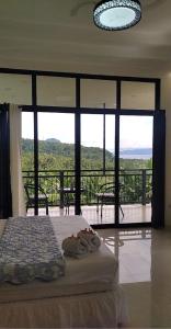 a bedroom with a bed and a balcony with windows at Taylor's Country Home- The Grande by Taylor's Traveller's Inn Second Floor in Catarman