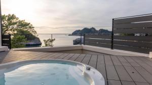 a hot tub on a deck with a view of the ocean at Mayu Futahari in Nishiizu