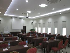 a conference room with tables and chairs and a screen at BAMBOO INN HOTEL & CAFE in Jakarta