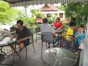 un grupo de personas sentadas en mesas en un patio en BAMBOO INN HOTEL & CAFE, en Yakarta