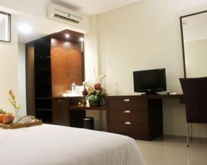1 dormitorio con 1 cama y escritorio con TV en BAMBOO INN HOTEL & CAFE, en Yakarta