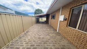 a hallway leading to a building with a fence at Puggle Palace, 21A Bower Street in Jurien Bay