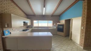 a large kitchen with white counters and a window at Puggle Palace in Jurien Bay
