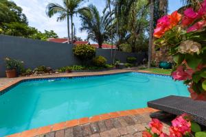 a swimming pool in a yard with flowers at Rozelee Rest 1 in Nelspruit