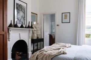 a white bedroom with a fireplace and a bed at Carrington House Daylesford in Daylesford