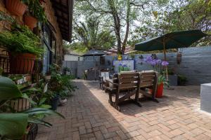 a patio with benches and an umbrella and plants at Rozelee Rest 1 in Nelspruit