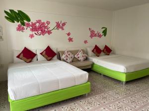 two beds in a room with flowers on the wall at ฟ้าประทานบูติกรีสอร์ท in Prachuap Khiri Khan