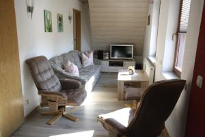 a living room with a couch and chairs and a tv at Ferienwohnung-Panoramablick in Neudorf