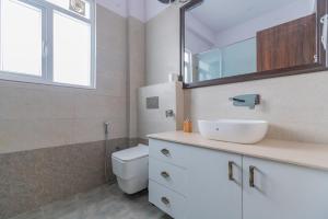 a bathroom with a sink and a toilet and a mirror at SaffronStays Polaris, Dehradun - pet-friendly Swedish home amidst nature in Dehradun