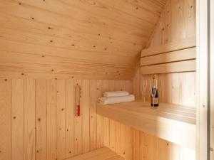 uma sauna de madeira com uma garrafa de vinho numa prateleira em Modern holiday home by the sea with sauna em Scherpenisse