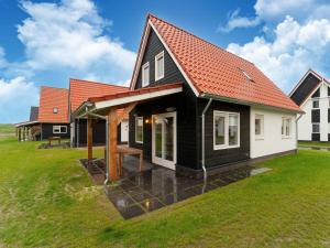una casa en blanco y negro con techo naranja en Modern holiday home by the sea with sauna en Scherpenisse
