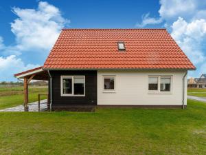 uma pequena casa com um telhado laranja em Modern holiday home by the sea with sauna em Scherpenisse