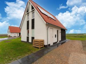 uma grande igreja branca com um telhado laranja em Modern holiday home by the sea with sauna em Scherpenisse