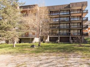 Un gran edificio de apartamentos con un parque enfrente. en Appartement cozy 4 pers avec parking privé à Serre-Chevalier - FR-1-330E-48, en Saint-Chaffrey