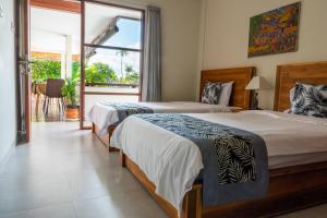 two beds in a hotel room with a balcony at House of Michella - Modern, Quiet & Central in Sanur
