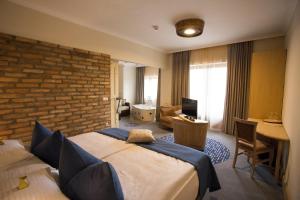 pokój hotelowy z łóżkiem i ceglaną ścianą w obiekcie Crocus Gere Bor Hotel Resort & Wine Spa w mieście Villány