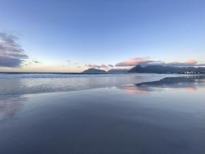 a beach with the ocean and mountains in the background at Rest@Kommetjie in Cape Town