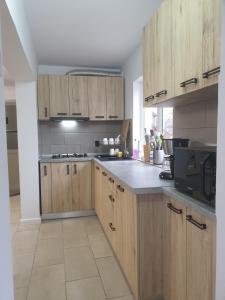 a kitchen with wooden cabinets and a microwave at Pensiunea Valea Veveritelor in Curtea de Argeş