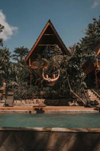 een huis met een zwembad ervoor bij Kusfarm Bali in Selemadeg