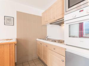 a kitchen with wooden cabinets and a white microwave at Appartement Briançon, 2 pièces, 6 personnes - FR-1-330C-17 in Briançon