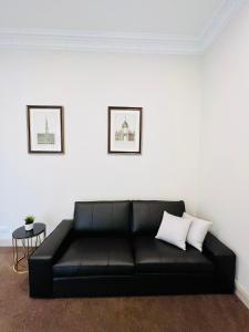 a black leather couch in a living room with two pillows at Clarendon Hotel in Melbourne