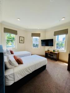 a bedroom with two beds and a desk and windows at Clarendon Hotel in Melbourne