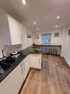 uma cozinha com armários brancos e bancadas pretas em 3 Laurel Court em Ulverston
