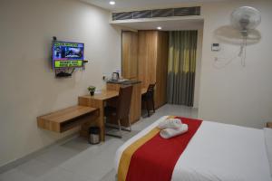 Habitación de hotel con cama, escritorio y TV. en Hotel Ambicas Grand en Visakhapatnam