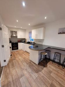 uma cozinha com armários brancos e um balcão preto em 3 Laurel Court em Ulverston