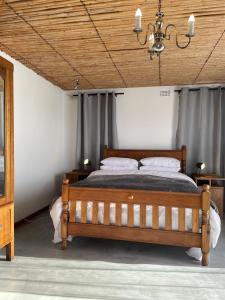 a bedroom with a wooden bed and a chandelier at Rest@Kommetjie in Cape Town
