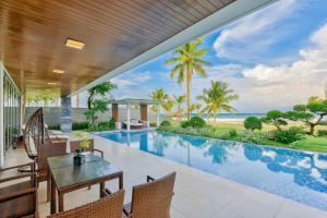 an outdoor patio with a swimming pool and the ocean at The Ocean Villa Resort Beachfront By Abogo in Da Nang