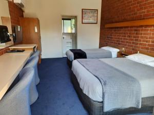 a hotel room with two beds and a brick wall at Abbotswood Motor Inn in Geelong