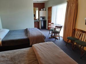 a hotel room with a bed and a table and chairs at Abbotswood Motor Inn in Geelong