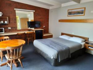 a hotel room with a bed and a table and a kitchen at Abbotswood Motor Inn in Geelong +47 photos