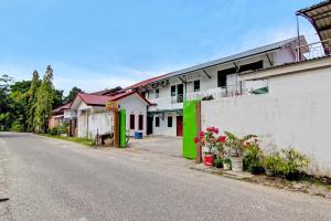 an empty street next to a white building with green accents at SPOT ON 91950 Guest House TekNong Syariah in Bangkinang