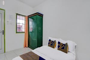 a room with a bed and a green door at SPOT ON 91950 Guest House TekNong Syariah in Bangkinang