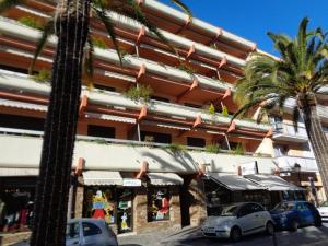 um edifício com palmeiras e carros estacionados em frente em Appartement Le Lavandou, 2 pièces, 4 personnes - FR-1-308-66 em Le Lavandou