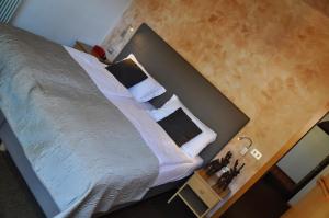 una camera da letto con un grande letto con lenzuola e cuscini bianchi di Residence Anda a Pozza di Fassa