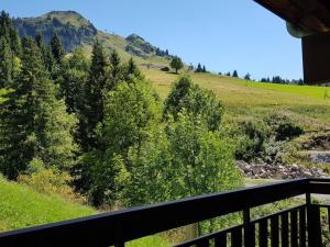 a balcony with a view of a field and trees at Appartement Le Grand-Bornand, 1 pièce, 4 personnes - FR-1-241-170 in Le Grand-Bornand