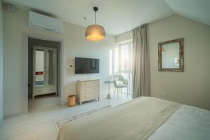 a white bedroom with a bed and a television at Arkady Hof Hotel in Stupava