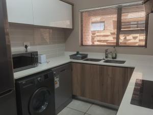 a kitchen with a washing machine and a microwave at Three Bedroom Apartment At The Blyde in Boschkop +5 photos